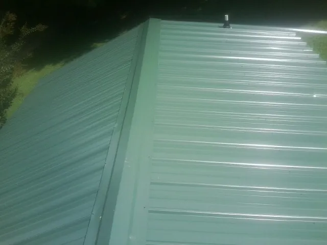 New green metal panels meeting at the ridge of a roof — Flat Roof Repair work by our crew in Valley View