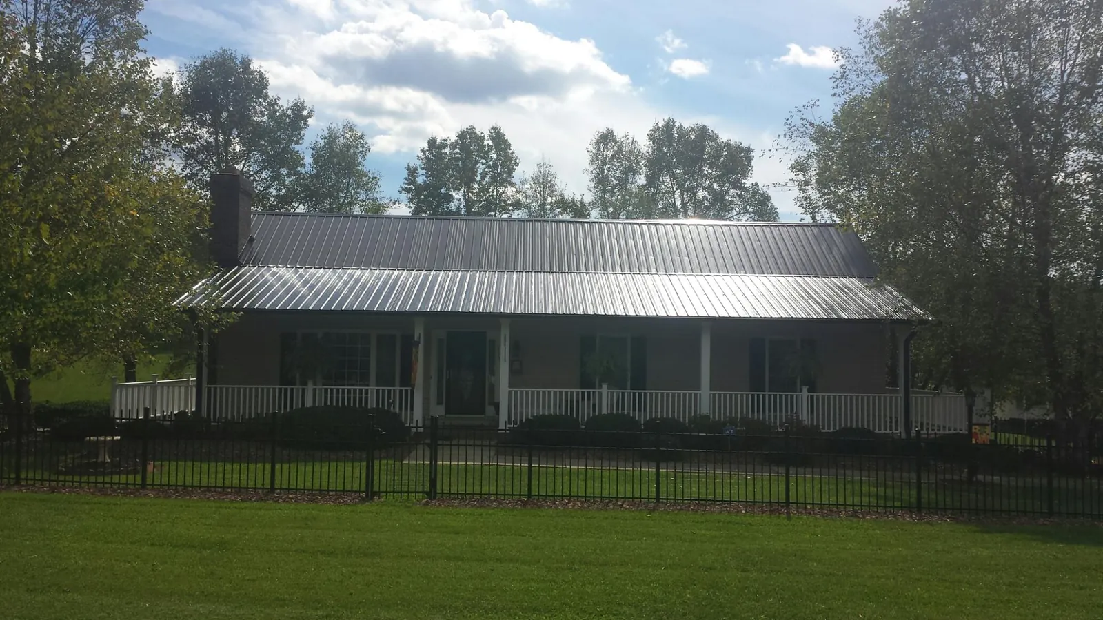 Gray metal roof on a brick ranch with a full width front porch — Gutter Guard Installation work by our crew in Valley View