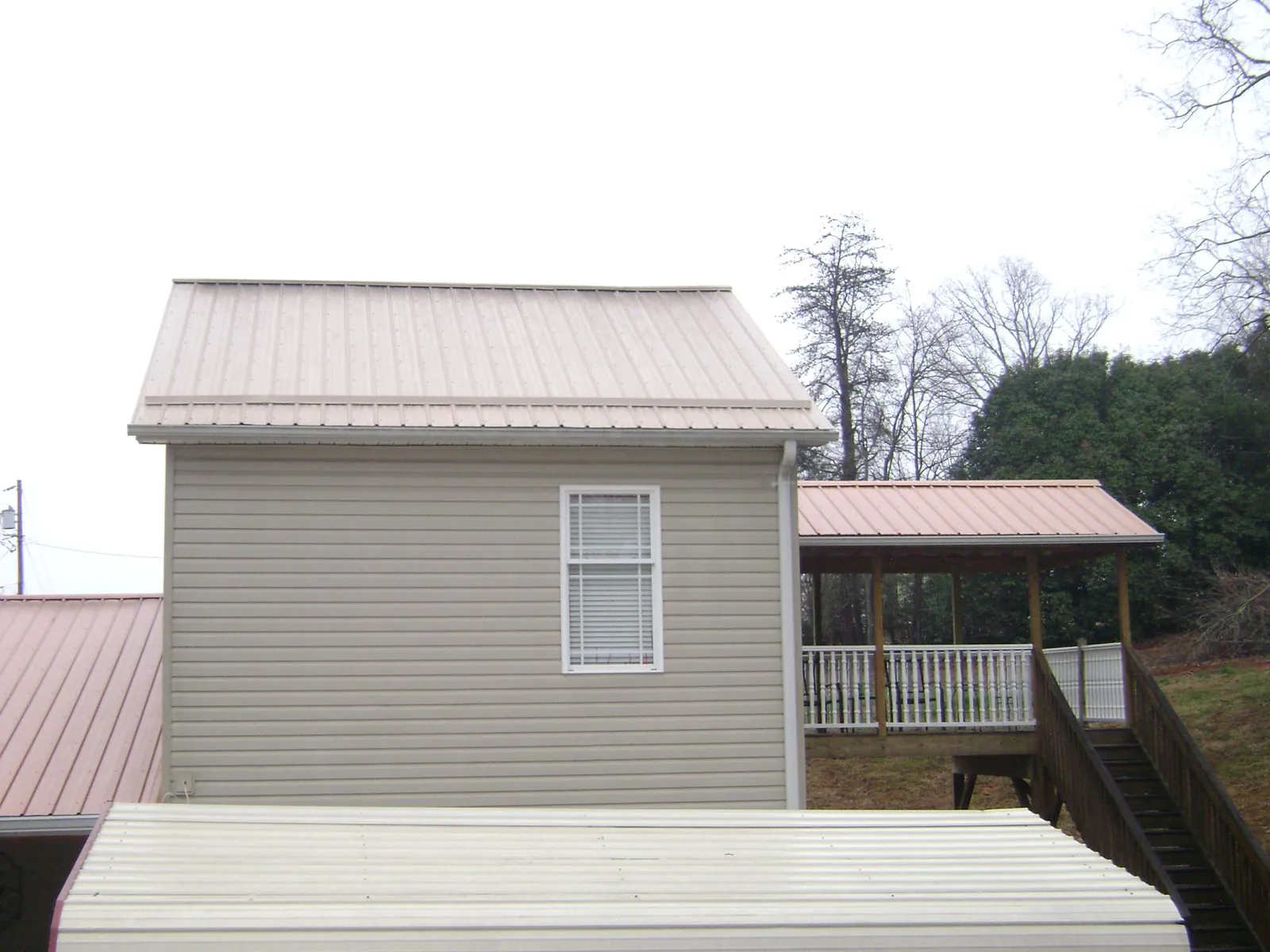 Tan metal roofs on a two story addition and attached porch, from a Roof Replacement job in Valley View