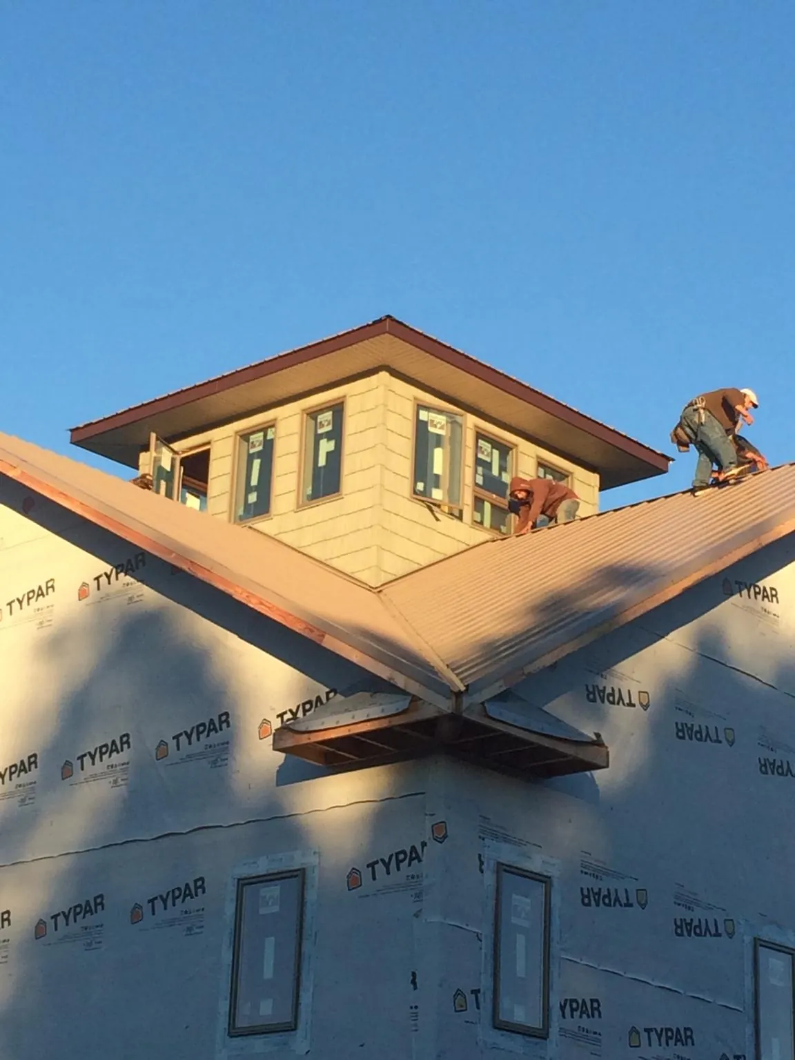 Roofers working around a rooftop cupola on a new metal roof at sunset — Roof Waterproofing in Valley View by Roofing Brothers